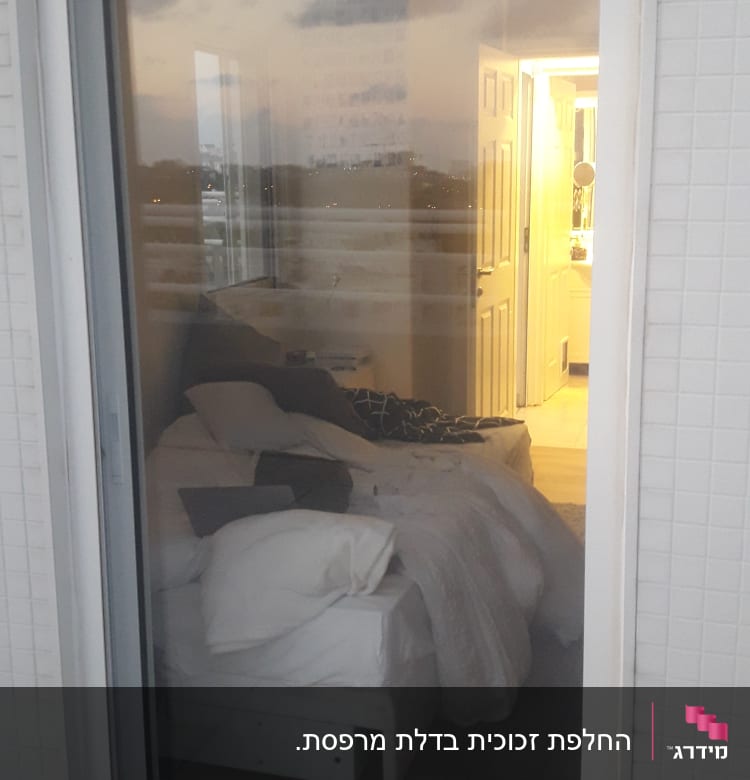 דלת זכוכית עם השתקפות חדר שינה מואר